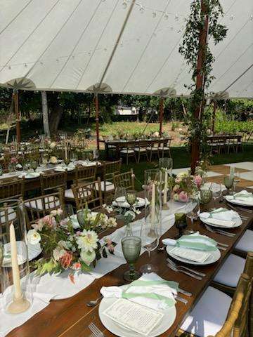 Sailcloth wedding tent with farm tables, floral centerpieces, and place settings for an outdoor wedding